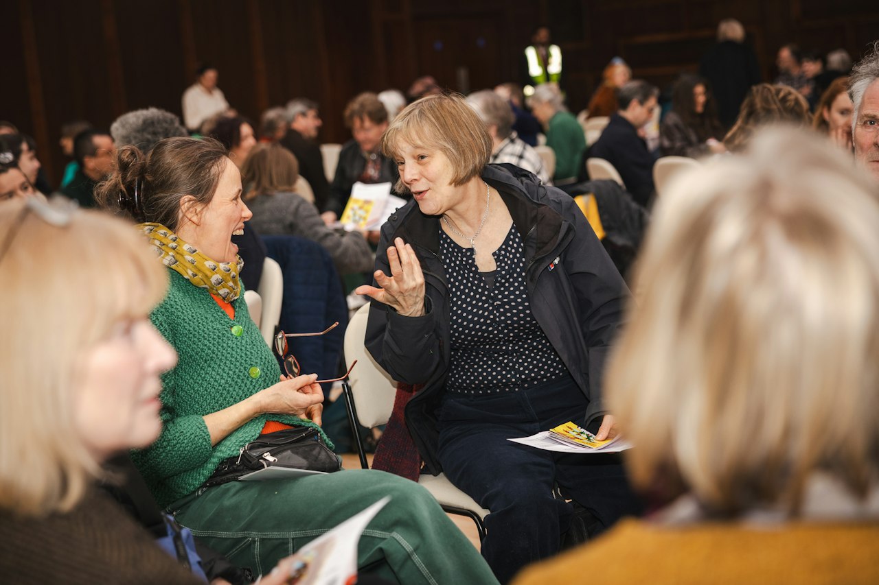 People at a busy Haringey Culture Collective event, chatting animatedly whilst sitting down