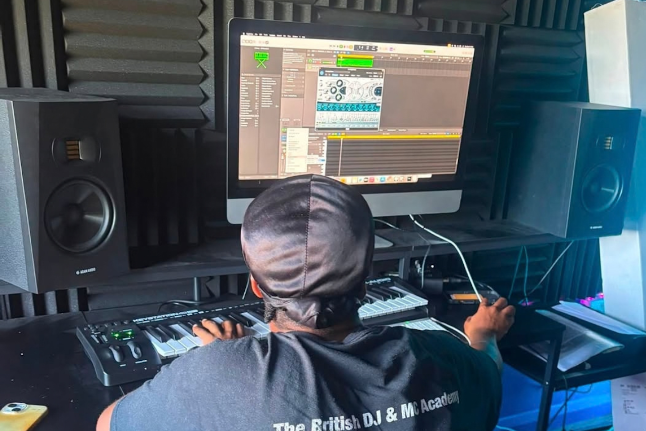 a young Black Man in a recording studio mixing sounds on a laptop
